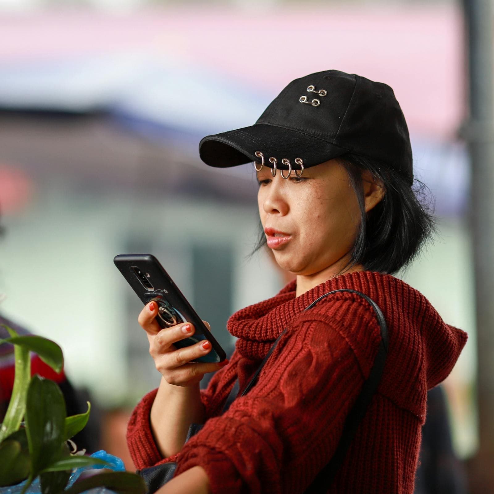 A shopper using a smartphone while browsing stalls at a market in Vietnam.